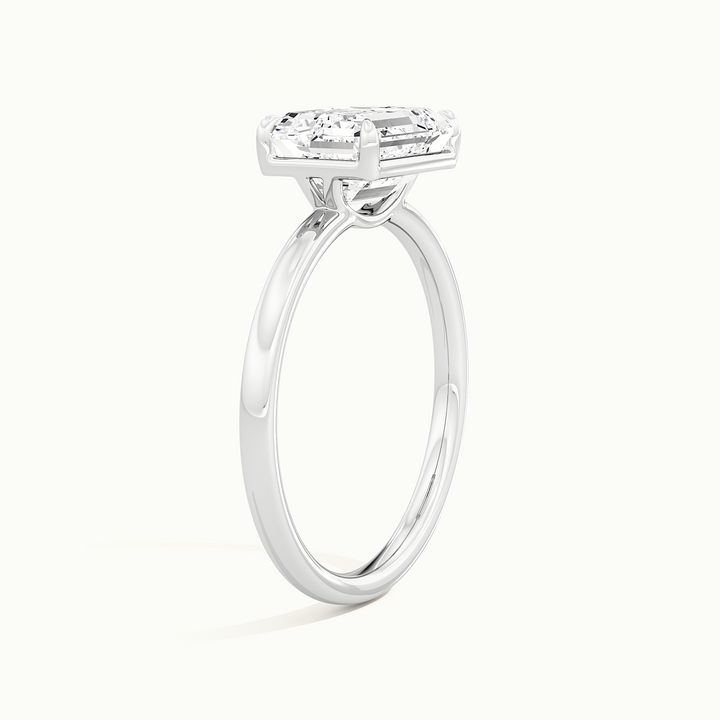 White gold emerald-cut east-west solitaire engagement ring, raised three-quarter view of the setting