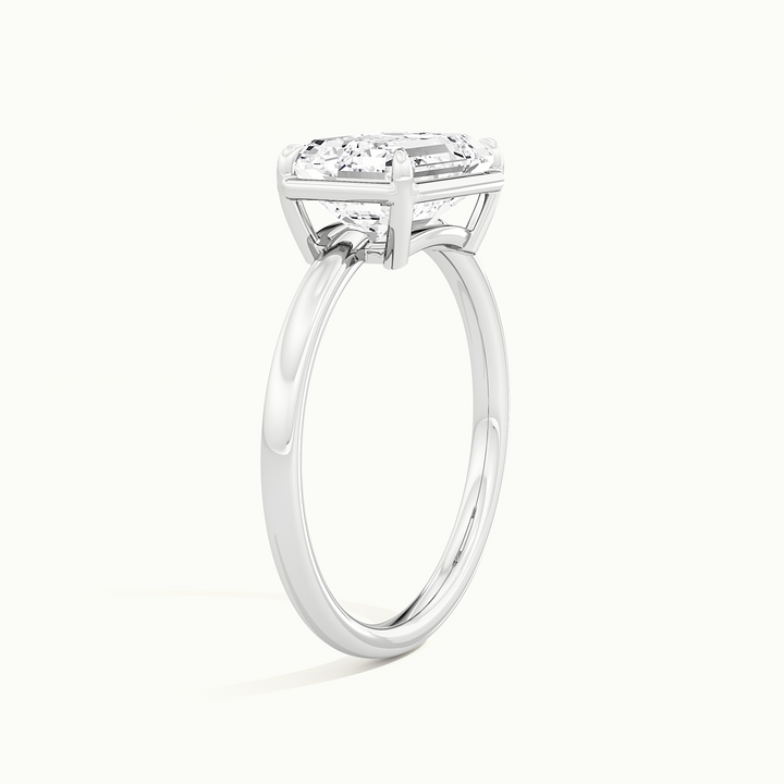 White gold emerald-cut east-west bezel-frame solitaire engagement ring, raised three-quarter view of the setting