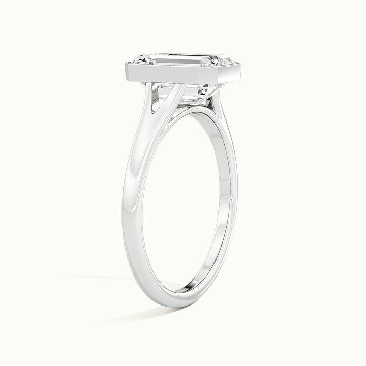 White gold emerald-cut bezel-set split shank solitaire engagement ring, raised three-quarter view of the setting