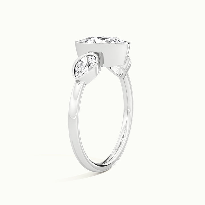 White gold oval-cut bezel-set three-stone with pear side stones engagement ring, raised three-quarter view of the setting