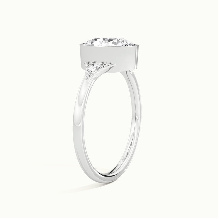 White gold oval-cut bezel-set with side-stone cluster engagement ring, raised three-quarter view of the setting